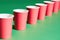 Diminishing perspective of red paper cup in row on green background