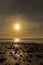 Dinas Dinlle beach with the sun setting reflected in the sea.  Beach holiday concept