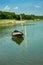 Dinghy boat tied to the water and green trees on the shore