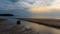 Dinghy sitting in tidal pool at beach at low tide during sunset with anchor trailing behind