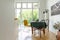 Dining chairs around a wooden table on a herringbone parquet floor of a white kitchen with open balcony