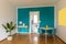 Dining room front view with small desk and turquoise wall. Open door to white kitchen and bright window