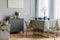 Dining room interior with long table, stylish golden chairs and grey wooden commode