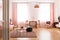 Dining table with chair in the middle of bright pastel pink living room in tenement house