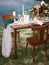 Dining table with floral decoration and festive table setting outdoor, seascape view