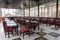 Dining table set up indoor with empty wooden chairs and glass tables, prepared for an event