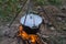 Dinner at the camp. The iron cauldron, blackened by the fire, hangs on a tripod over the fire