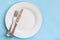 Dinner plate, knife and fork on blue background