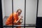 Dinner in a prison cell. A prisoner eats tasteless food from an iron bowl under guard behind bars.