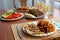 Dinner table with salad dish, chicken, sweet potatoes, bread and colorful water glass