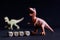 Dino lettering next to toy dinosaurs on a dark background. The concept of an educational children`s game and the study of