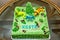 A dinosaur birthday cake. Children`s holiday cake decorated with dinosaurs in the Jurassic period jungle.
