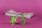 Dinosaur miniatures and a wad of bills against a purple background. A wad of cash in the background . Green figures of animals of