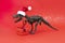 Dinosaur skeleton in Santa hat stand on a red background with New Year`s gift. Old New Year concept