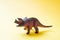 Dinosaur on a yellow background. Plastic rubber toy. Selective focus