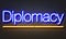 Diplomacy neon sign on brick wall background.