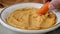 Dipping a baby carrot into a bowl of fresh hummus