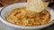 Dipping a corn tortilla chip into a bowl of hummus slow motion