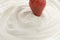 Dipping fresh strawberry into cream