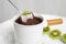 Dipping kiwi into fondue pot with chocolate on table