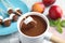 Dipping marshmallow into fondue  with milk chocolate on light table, closeup