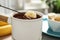 Dipping slice of  into fondue pot with milk chocolate on table indoors, closeup