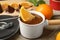 Dipping slice of orange into fondue pot with milk  on wooden table, closeup