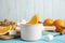 Dipping slice of orange into pot with chocolate fondue on blue table