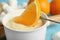 Dipping slice of orange into  with white chocolate fondue, closeup