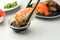 Dipping tasty sushi into soy sauce at white table, closeup. Space for text