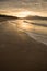 Direct golden sunset`s sunlight on a scenic sandy beach in hendaye in dramatic cloudy atmosphere, basque country, france