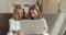 Direct view of two little smiling sisters looking at laptop. Portrait of girls children use computer to watch cartoons