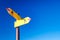 Directional marker for a mountain hike. Yellow bright sign with an arrow against the blue sky.