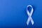 Directly above shot of blue stomach cancer awareness ribbon isolated against blue background