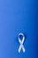 Directly above shot of blue stomach cancer awareness ribbon isolated on blue background, copy space