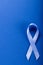 Directly above shot of blue stomach cancer awareness ribbon isolated over blue background