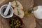 Directly above shot of olives with oil bottle and bread by spices in mortar pestle on crumbled paper