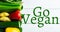 Directly above view of go vegan text by fresh vegetables on wooden table