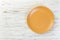 Directy above Empty orange matte plate on white wooden background with copy space