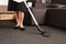 Dirt have no chances to survive. Cropped portrait of woman in maid uniform cleaning floor with vacuum cleaner, working