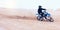 Dirt, motorbike and athlete driving with speed in sports, adventure and sand in desert or man riding outdoor with sky or