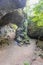 Dirt path to a small tunnel passing a huge sandstone rock formation, exposed roots of a trees