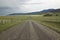 Dirt road into Centennial Valley, Montana with incoming storm, green fields and mountains