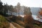 Dirt road, Distance view. Morning landscape. Pine forest, sun rays, glow, river lake, mountains. Summer camping warm colors.