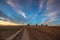 On the dirt road between empty field after harvesting in summer evening