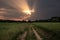 Dirt road through the field at sunset. Beautiful summer landscape.