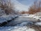 Dirt road with frozen ponds and snow-covered vegetation by the road, winter landscape