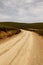 Dirt road with grass on the sides with the mountains ahead