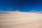 Dirt road at high altitude with sandy desert and barren volcano range on the Andean highlands. Road trip to the famous Uyuni Salt