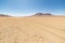 Dirt road at high altitude with sandy desert and barren volcano range on the Andean highlands. Road trip to the famous Uyuni Salt